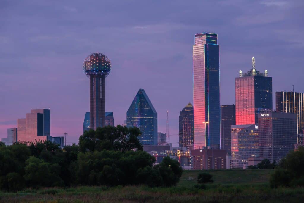 Downtown Dallas skyline at dusk with colorful building lights and Reunion Tower.