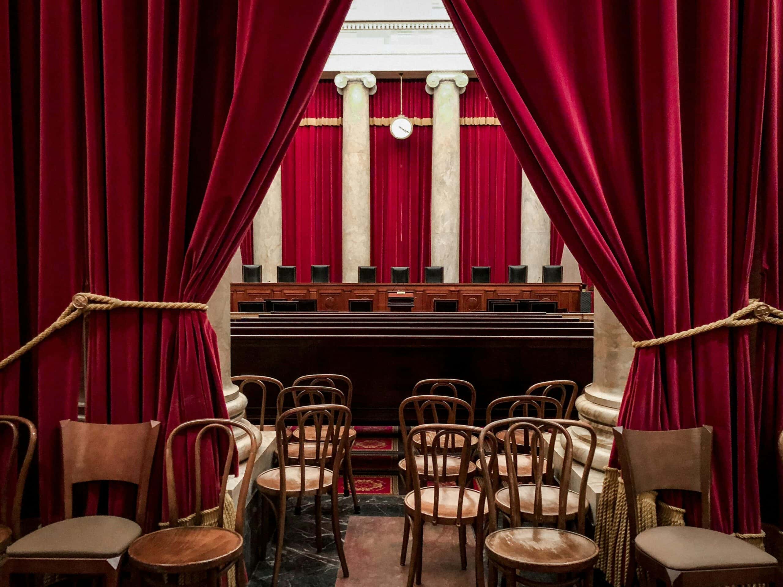 Elegant courtroom with red velvet curtains and wooden chairs, ideal for legal proceedings or events.